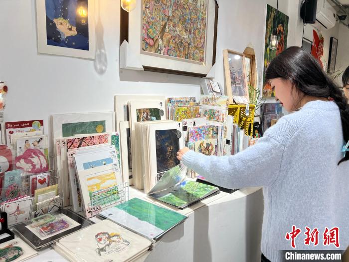 圖為藝術品商店內，顧客挑選插畫作品。　鐘旖 攝