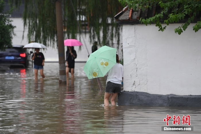 7月31日，市民行走在雨中的北京房山區瓦窯頭村。北京市氣象臺當日10時發布分區域暴雨紅色預警信號。北京市水文總站發布洪水紅色預警，預計當日12時至14時，房山區大石河流域將出現紅色預警標準洪水。<a target='_blank' href='/'><p  align=