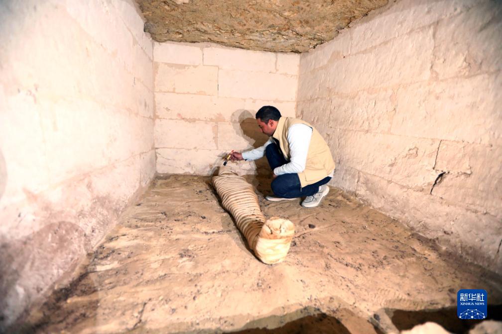 10月15日，在埃及明亞省考古現場，考古人員清理一座石鑿墓中的木乃伊。新華社發（艾哈邁德·戈馬攝）