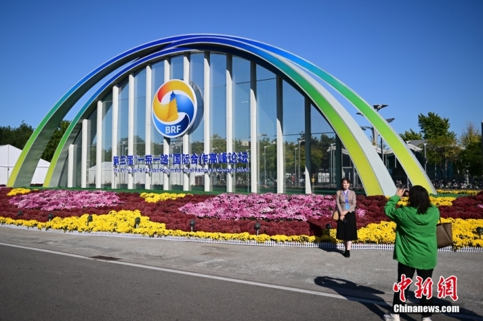 10月15日，北京，工作人員在國家會議中心外的第三屆“一帶一路”國際合作高峰論壇景觀布置前拍照留念。當(dāng)日，位于國家會議中心的第三屆“一帶一路”國際合作高峰論壇新聞中心啟動試運(yùn)行。據(jù)悉，第三屆“一帶一路”國際合作高峰論壇將于10月17日至18日在北京舉行。<a target='_blank' href='/'><p  align=