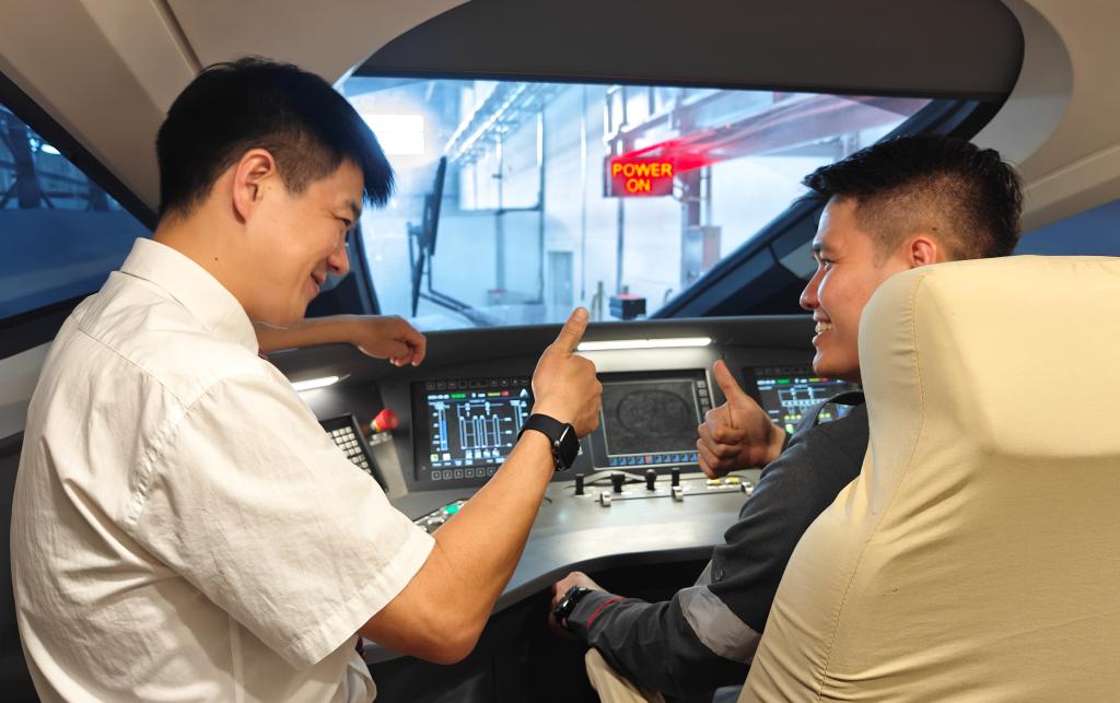 8月25日，在印度尼西亞萬隆的雅萬高鐵德卡魯爾動車所內，中國師傅穆振（左）在向印尼火車司機塞蒂亞萬講解動車組出庫前的上電作業(yè)。