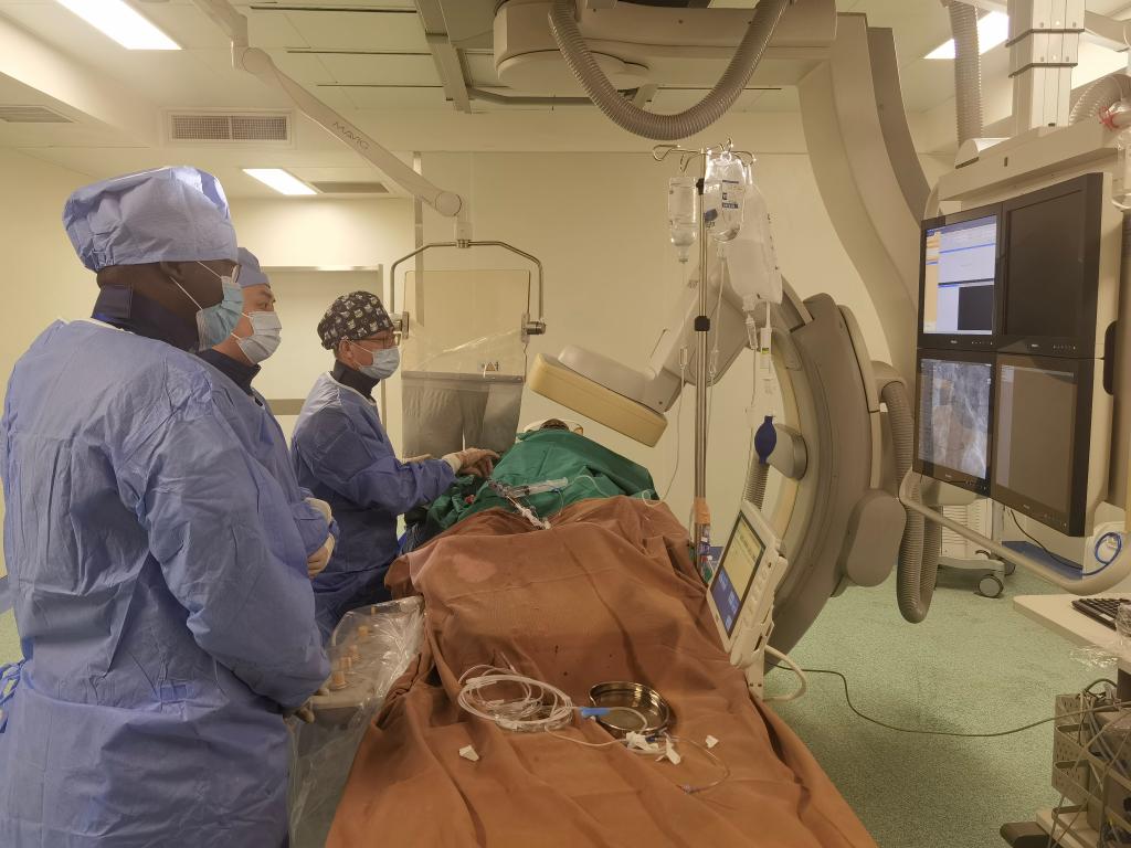 中國第29批援幾內亞醫療隊隊員、首都醫科大學附屬北京天壇醫院心內科副主任醫師王汝朋（右一）正在給患者做手術。（北京天壇醫院供圖）