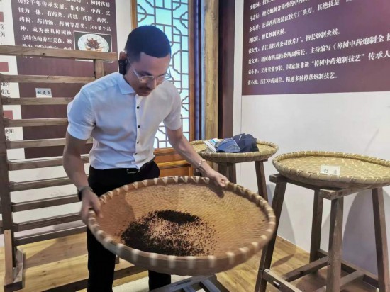 2023“一帶一路”媒體合作論壇聯合采訪團團員在非遺文化展示館體驗中藥炮制技藝。（本報記者 黃超攝）