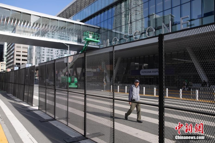 當地時間11月10日，一名行人從美國舊金山莫斯康中心周圍的金屬圍欄旁經過。隨著亞太經合組織(APEC)第三十次領導人非正式會議臨近，作為會議場地的莫斯康中心附近出現金屬圍欄，執勤警察也大幅增加。<a target='_blank' href='/'><p  align=