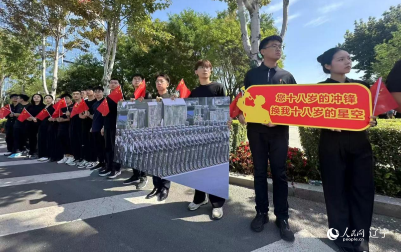 沈陽市人民廣場上,大學生們手持閱兵的圖片,告慰英烈。人民網記者 周頌雪攝