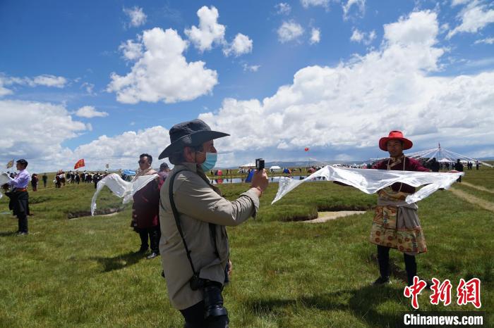 圖為一名外籍攝影師記錄當?shù)夭刈鍤g迎儀式。　馬銘言 攝