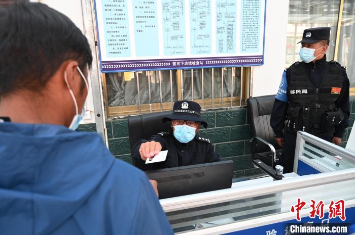 圖為移民管理警察登記完身份信息后將證件歸還給行人?！≮w朗 攝