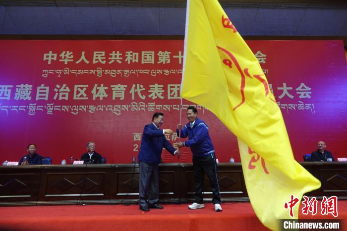 西藏自治區副主席甲熱·洛桑丹增授代表團團旗，西藏自治區體育局局長尼瑪次仁接旗。　冉文娟 攝