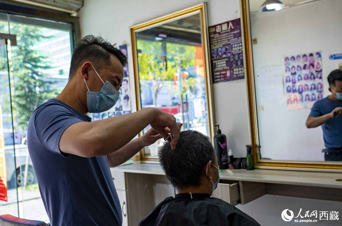 理發店老板為顧客理發。次仁羅布 攝