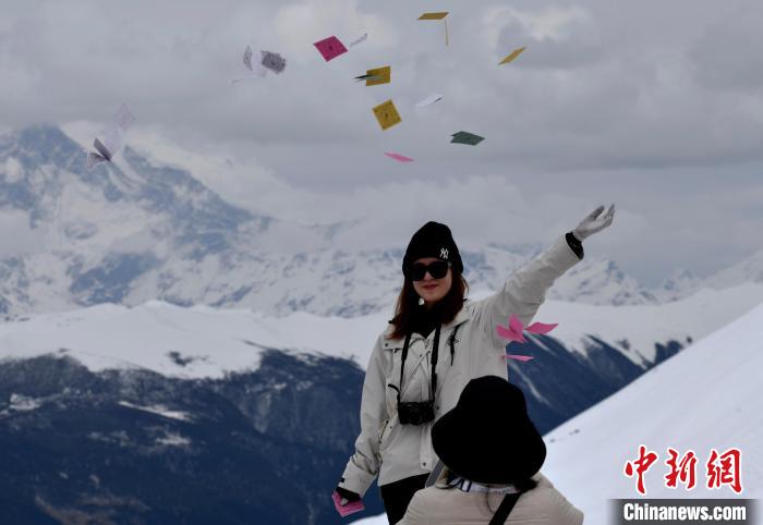 圖為5月14日，游客在西藏林芝色季拉山觀景臺拋灑“隆達”(風馬旗，藏族民眾的一種祈福方式)?！±盍?攝